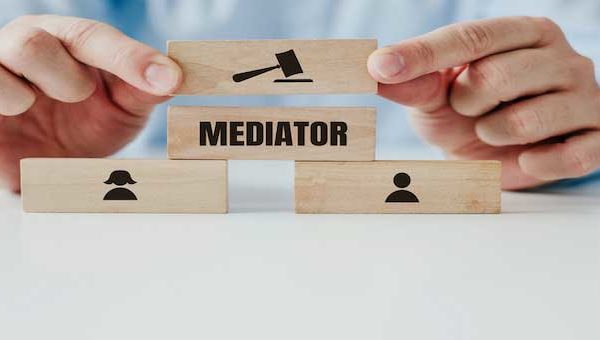 A man dressed in a blue shirt holds wooden blocks with a stamp of a man, a woman and a referee's hammer in his hands. The concept of divorce and mediation. Marriage agreement before a court.